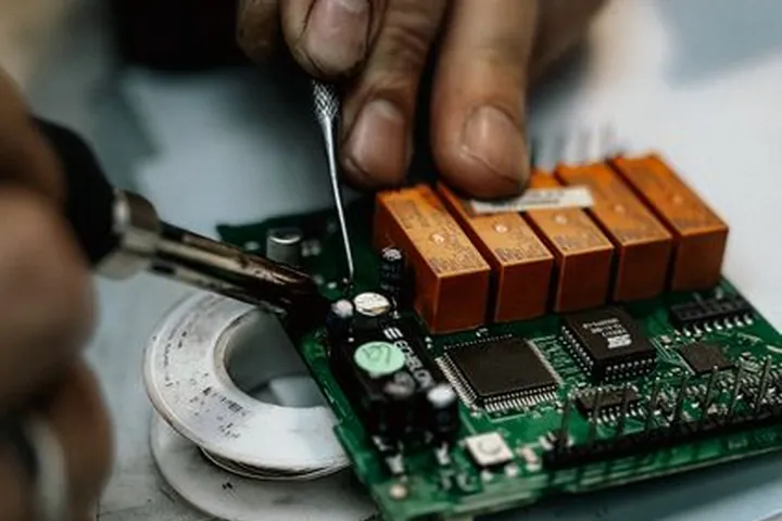 Close-up of a technician repairing a circuit board with a soldering tool